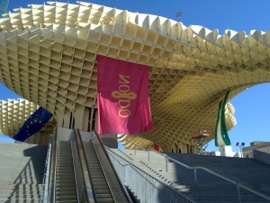 Escalators and stairs up to the first-floor Plaza Mayor, the concert and event space, with Seville city's flag.