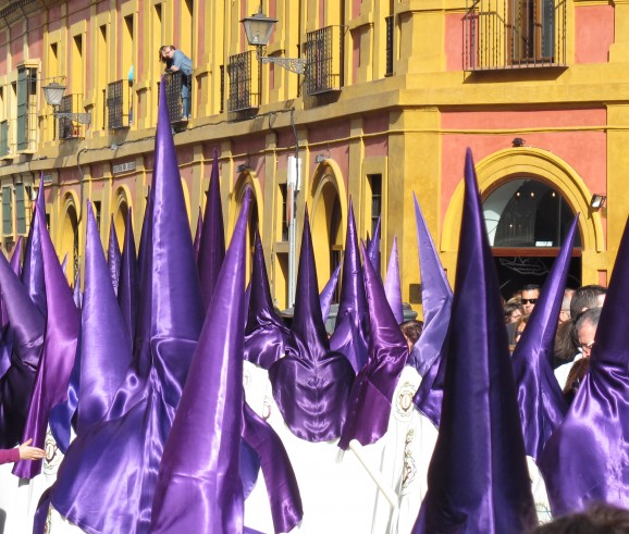 Nazarenos in a Holy Week procession along a street in Seville.