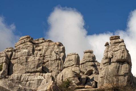 Limestone towers of El Torcal rise dramatically beneath a vivid blue sky and white clouds.