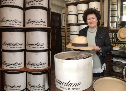 Cristina Vega inside her historic hat shop, Sombrerería Maquedano in Seville, with towers of vintage hatboxes. © Fiona Flores