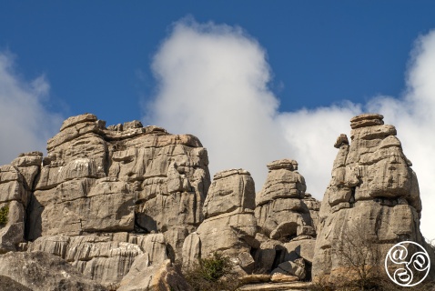 Limestone towers of El Torcal rise dramatically beneath a vivid blue sky and white clouds.