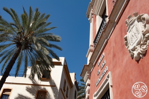 Looking up at the brilliant blue sky of Seville from Plaza San Francisco, framed by towering palms and the intricate details of ornate Spanish architecture. A moment of serenity in the heart of the city. © Michelle Chaplow