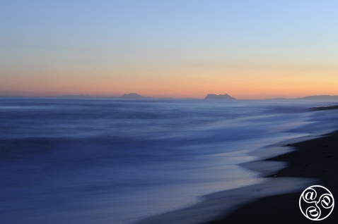 Looking out to the Two Pillars of Hercules on the horizon at sunset, as the sky glows with warm hues © Michelle Chaplow